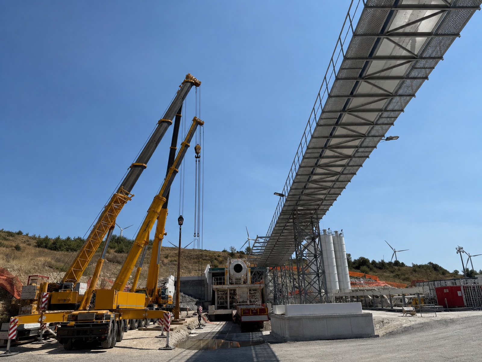 Cantiere infrastrutturale con gru e passerella metallica in fase di montaggio